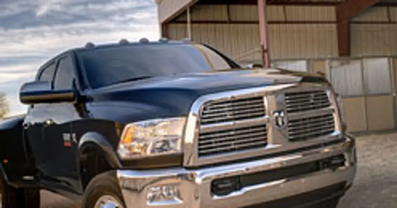 Ciemny Dodge Ram 3500 z chromowanym grillem i błyszczącym lakierem stoi przed budynkiem.