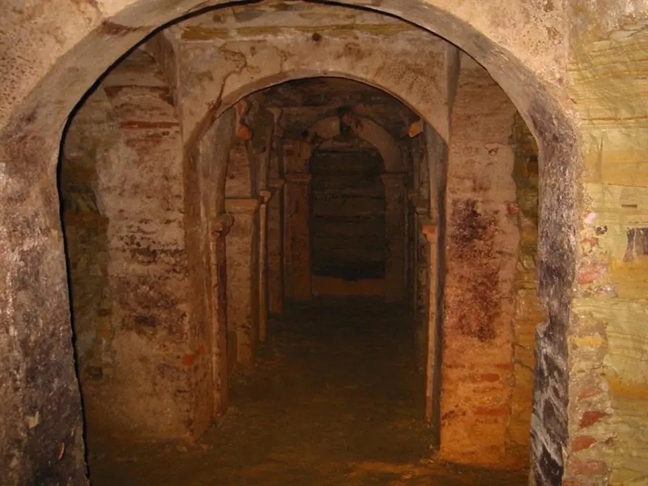 Corridoio sotterraneo con archi in mattoni e pietra a Monsampolo del Tronto, evocando misteri antichi.
