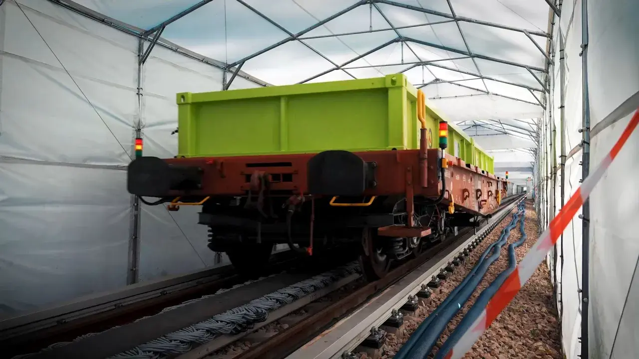 Zielony wagon towarowy na torach pod namiotem. Może to być pierwsza kolej na świecie w takim wydaniu.
