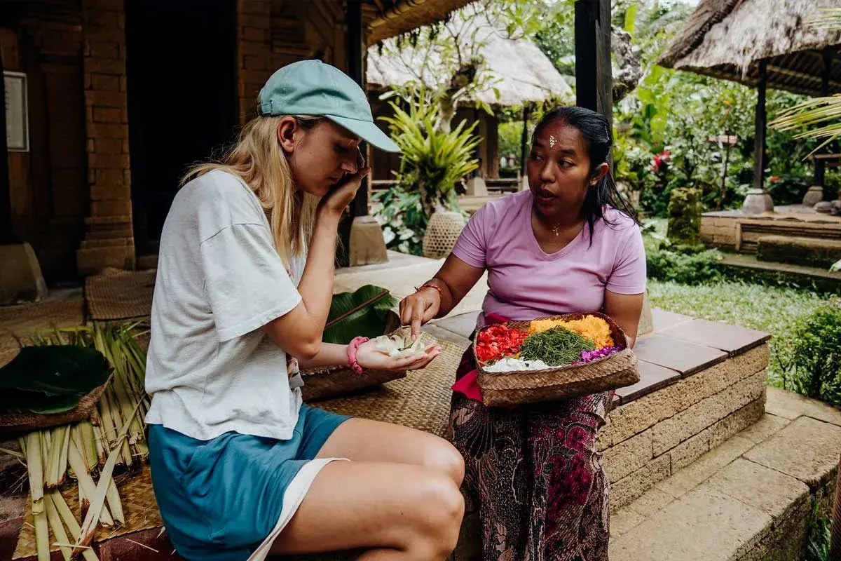 Une touriste apprend à faire des offrandes avec sa guide à Bali.