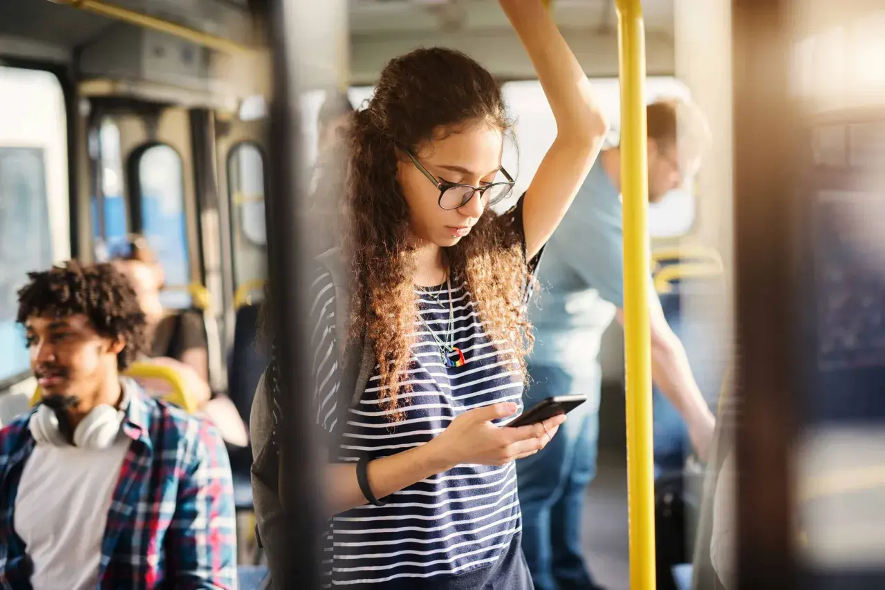 Ragazza sul bus guarda il suo telefono, forse controllando l'orario della metro linea A di Roma per il suo prossimo viaggio.