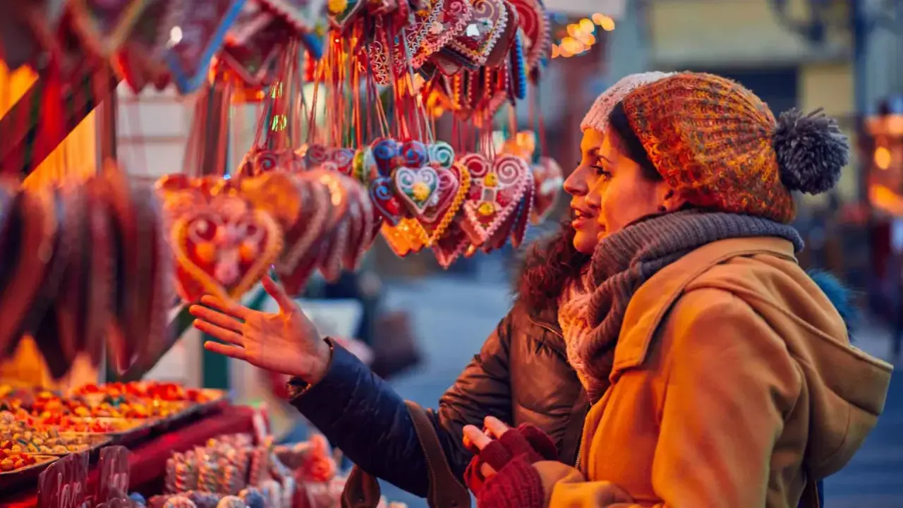 Dos mujeres admiran dulces y galletas en forma de corazón en un mercadillo de Santillana del Mar.