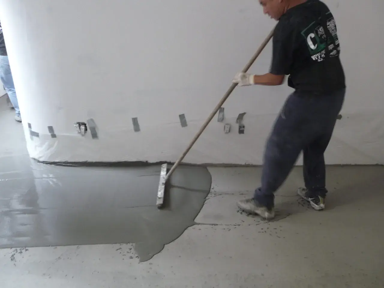 Man behandla betonggolv inomhus med en bredspackel för att jämna ut det flytande materialet.
