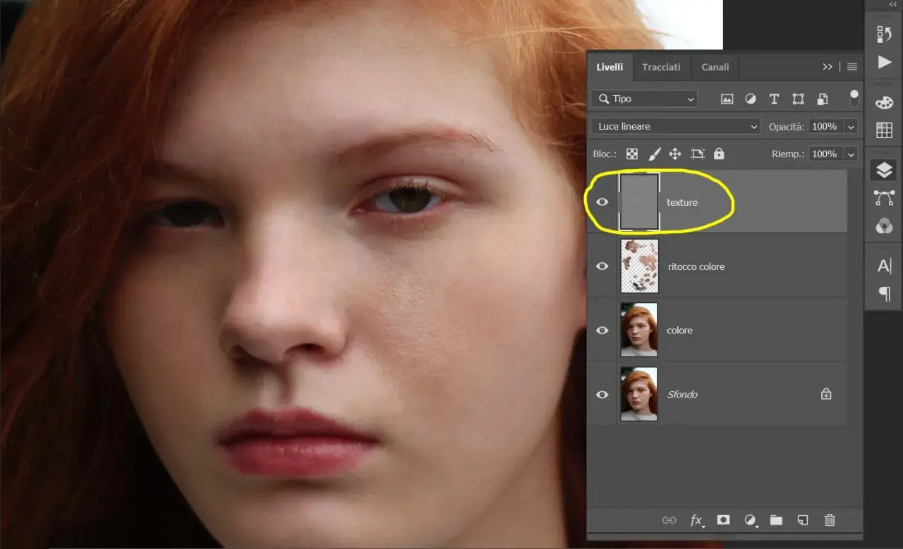 Primo piano di un volto femminile con capelli rossi. Pannello Livelli di Photoshop aperto, evidenziato il livello "texture" per la separazione delle frequenze.