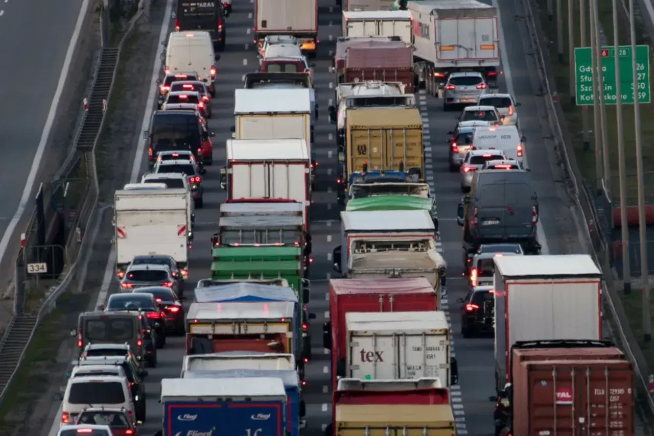 Korek na autostradzie, mnóstwo ciężarówek i samochodów. Widać znaki informujące o zakazie jazdy ciężarówek.