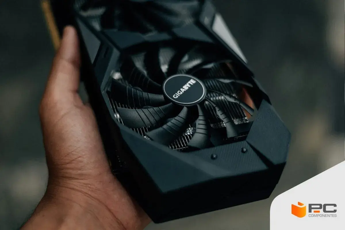 Mano sostiene una tarjeta gráfica Gigabyte, esencial para el rendimiento de tu PC.
