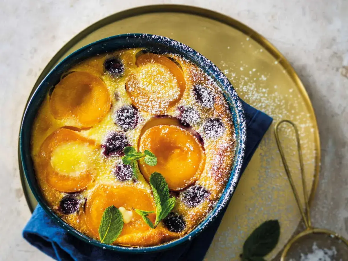 Un délicieux clafoutis abricot, saupoudré de sucre glace et garni de feuilles de menthe fraîche.