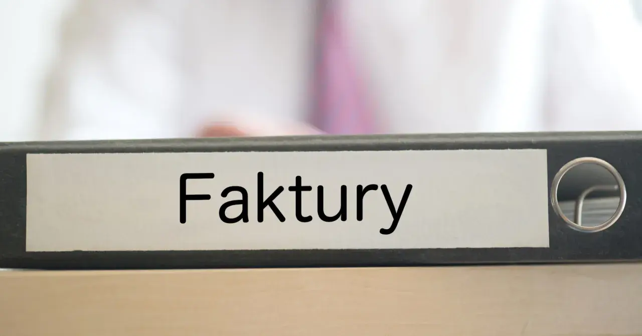 Segregator z napisem "Faktury" na biurku, gotowy do uporządkowania dokumentacji.