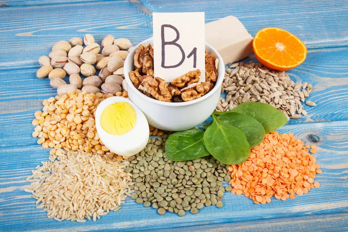 Vielfalt an vitamin b1 lebensmittel: Nüsse, Linsen, Reis, Erbsen, Ei, Spinat, Sonnenblumenkerne, Orange und Hefe.