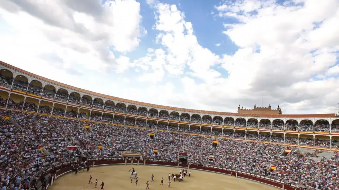 Gran multitud asiste a una corrida de toros. El sol brilla en el cielo azul con nubes blancas. ¡Una visita a la plaza de toros es una experiencia inolvidable!