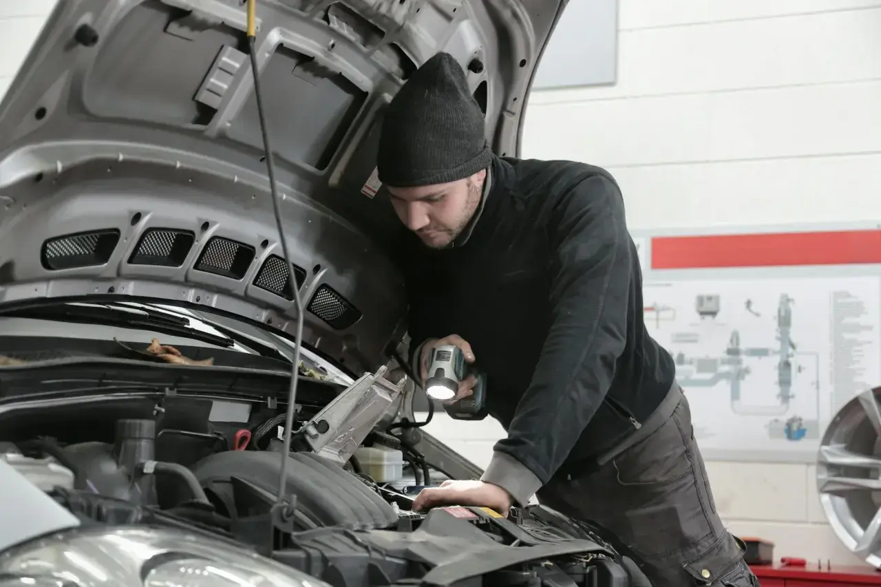 Mechanik bada przyczyny nagłego spadku mocy silnika powyżej 3000 obrotów, oświetlając silnik latarką.