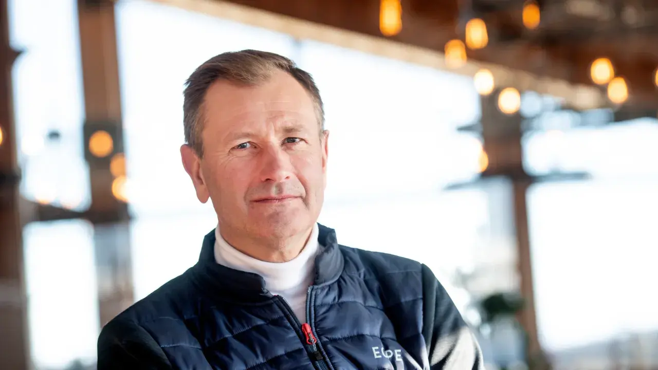 SkiStar VD, Stefan Söderberg, bär en blå dunjacka över en vit polotröja. Bakgrunden är suddig med ljus och trädetaljer.