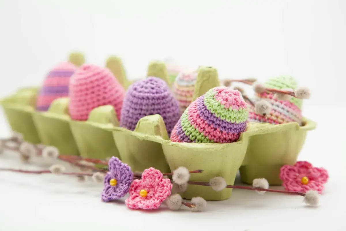 Uova di Pasqua all'uncinetto in un portauova verde, perfette per idee lavoretti con la lana facili e colorati.