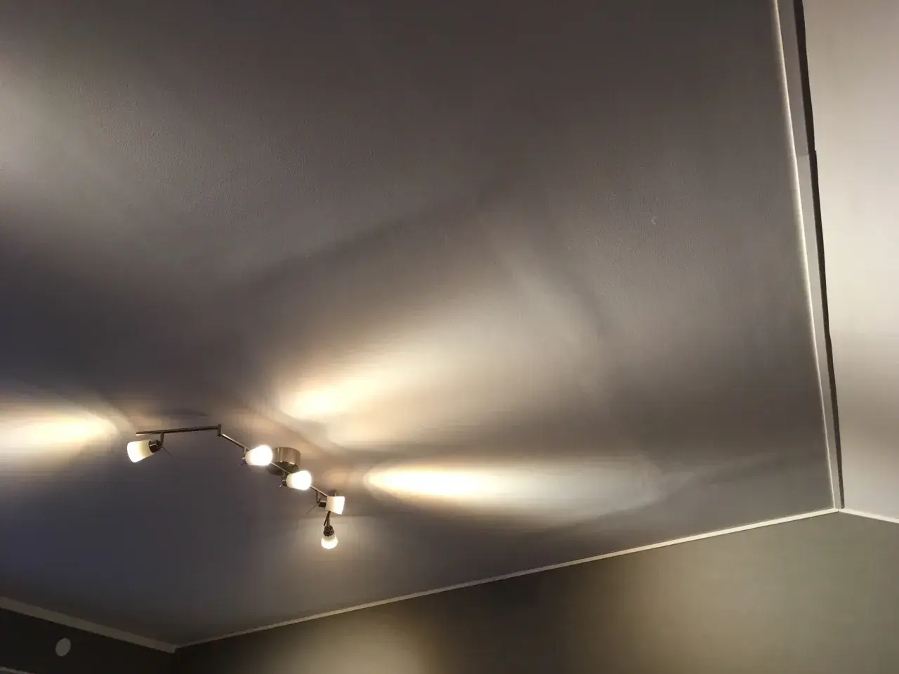 Taket är gipsat och skarvarna är spacklade. En taklampa med flera spotlights lyser upp rummet.
