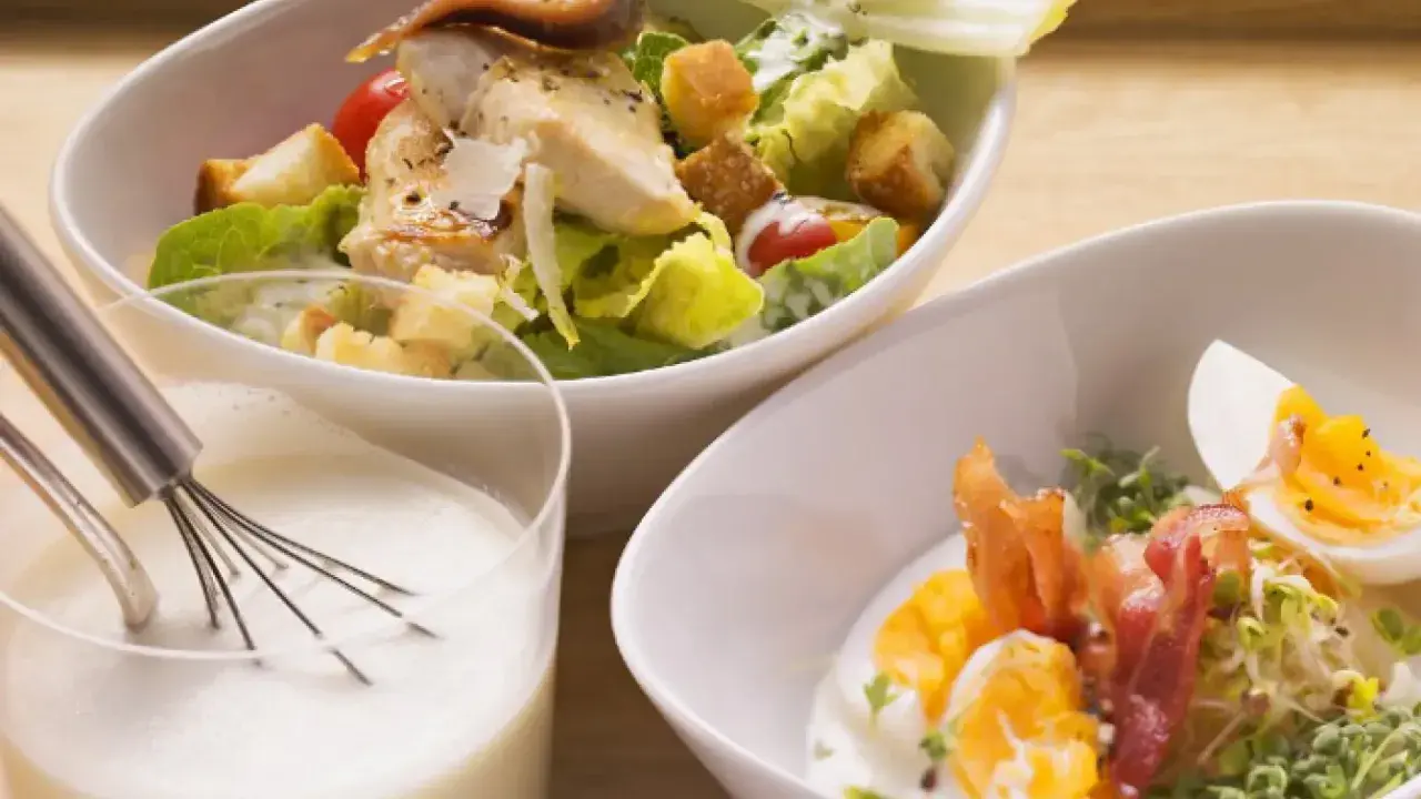 Ensalada César con pollo y huevo duro, acompañada de una cremosa salsa césar vegana.