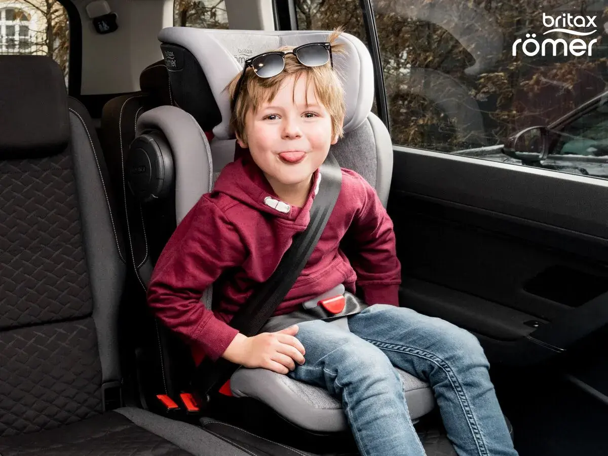 Chłopiec w foteliku samochodowym Britax Römer, z językiem na wierzchu, w okularach przeciwsłonecznych na głowie. Jaki fotelik samochodowy wybrać?