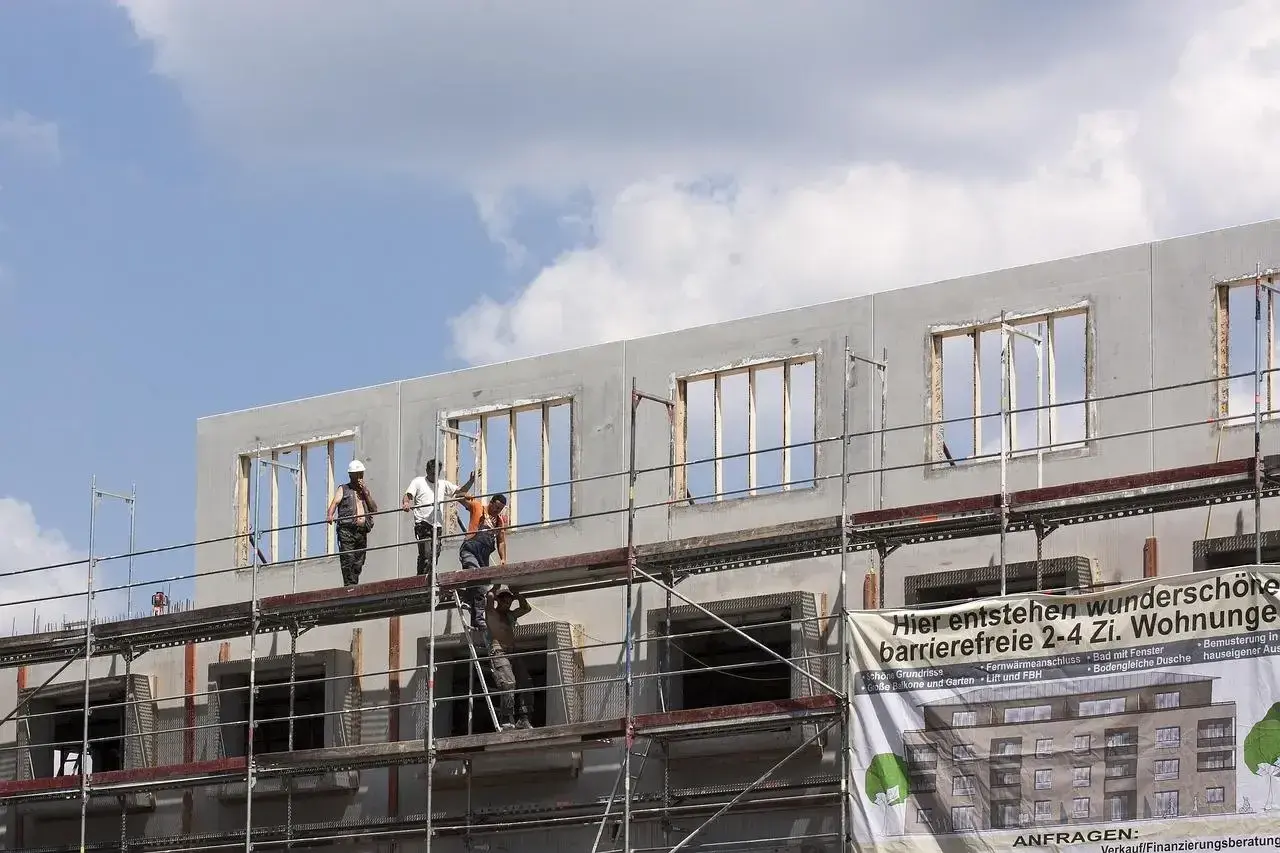 Chantiers de construction : des ouvriers sur des échafaudages travaillent sur un immeuble en cours de construction, projet de crédit immobilier avec travaux.