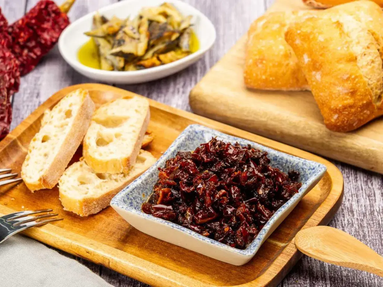 Pericana receta: pan rústico, pimientos secos y un cuenco con la deliciosa pericana, lista para untar.