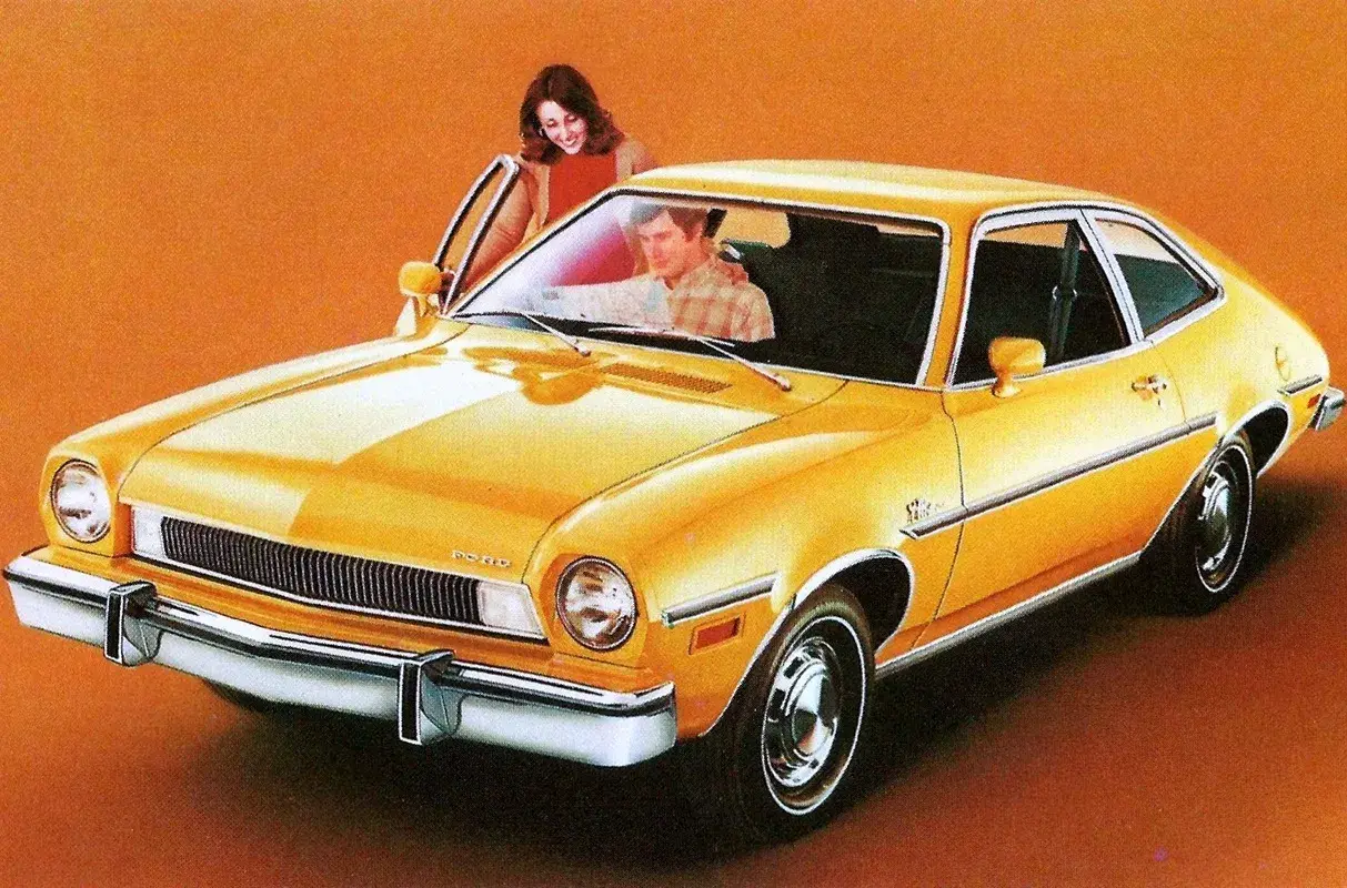 Gul Ford Pinto med en kvinna som öppnar dörren och en man i förarsätet.