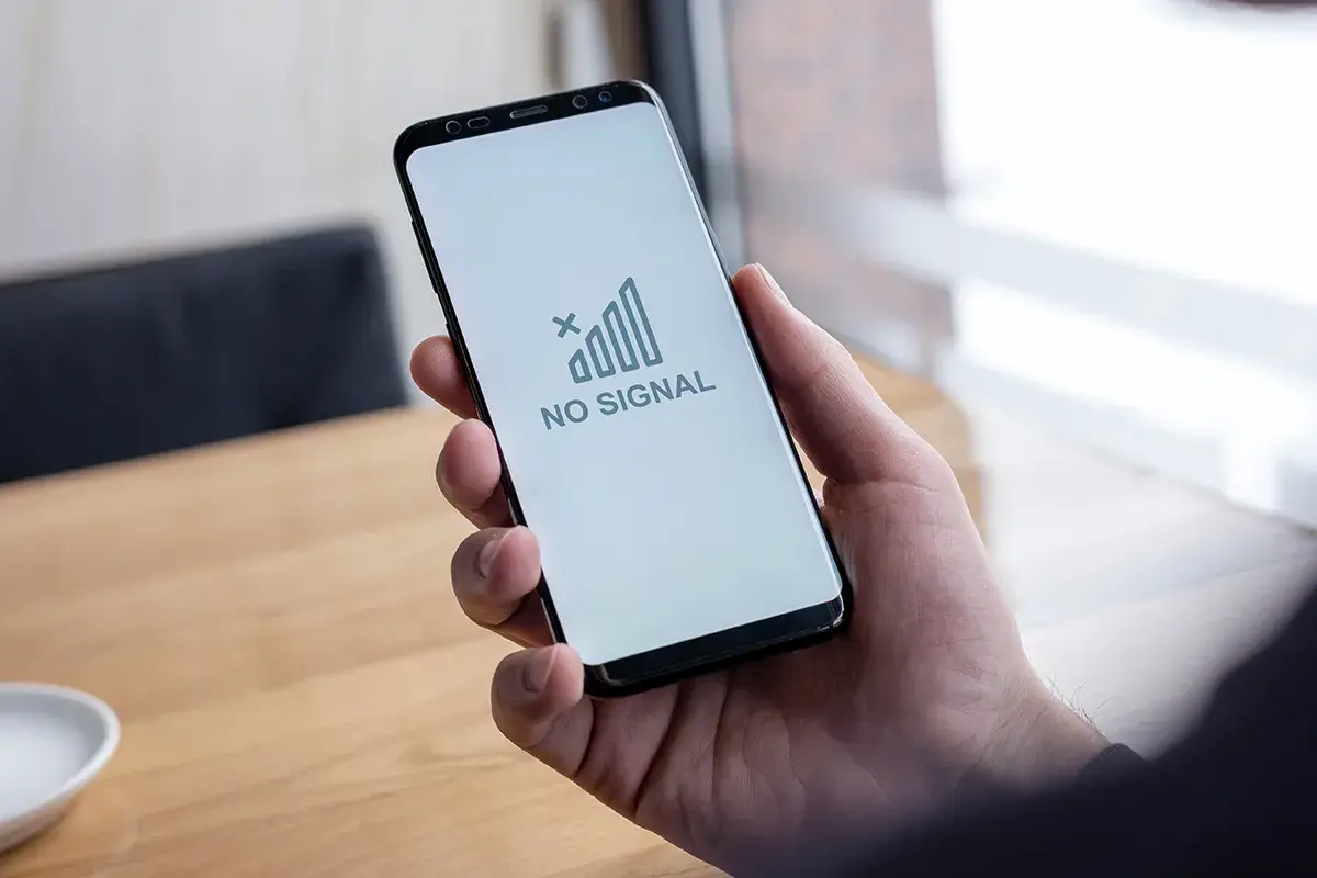 Dłoń trzyma smartfon z napisem "NO SIGNAL". To wyjaśnia, dlaczego nie mogę wysłać MMS.