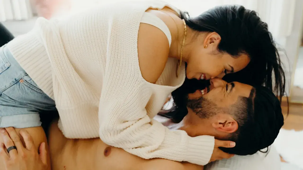 A couple embracing intimately, with the woman leaning over the man.