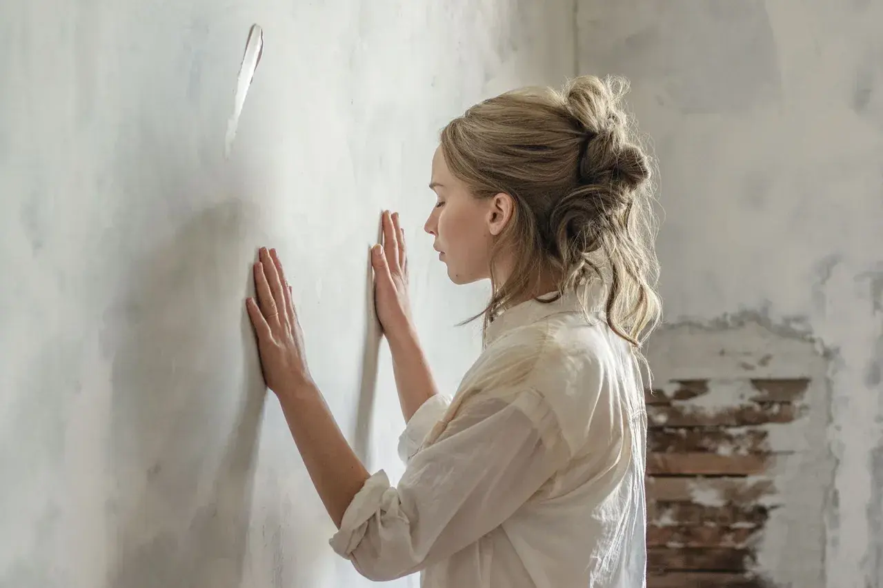 Donna con le mani sul muro, forse in attesa di una notizia o in un momento di riflessione. Una madre in attesa, la sua recensione interiore.