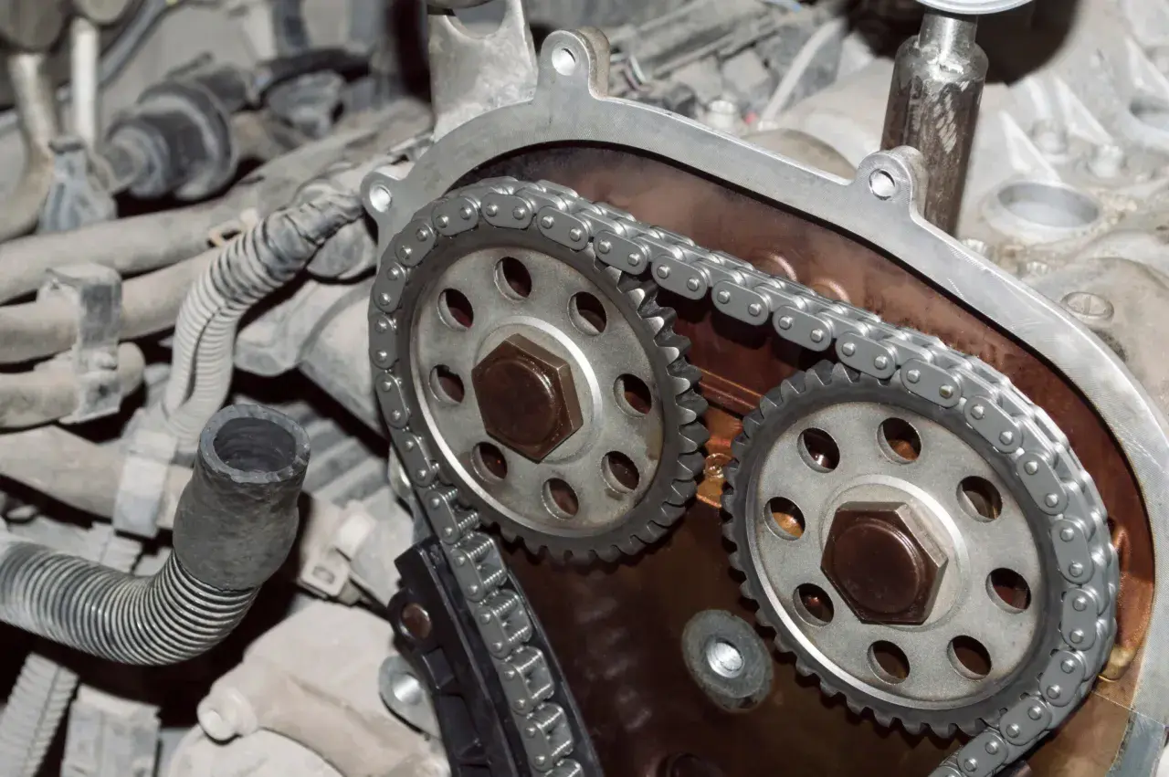 Primer plano de un motor con cadena de distribución, mostrando los engranajes y la cadena metálica.