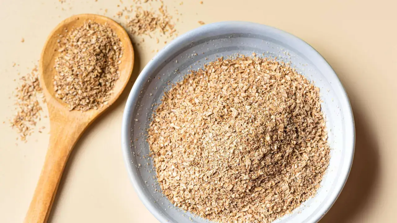 Eine Holzschale und ein Löffel gefüllt mit Haferkleie. Haferkleie ist ein nährstoffreiches Nebenprodukt der Haferverarbeitung.