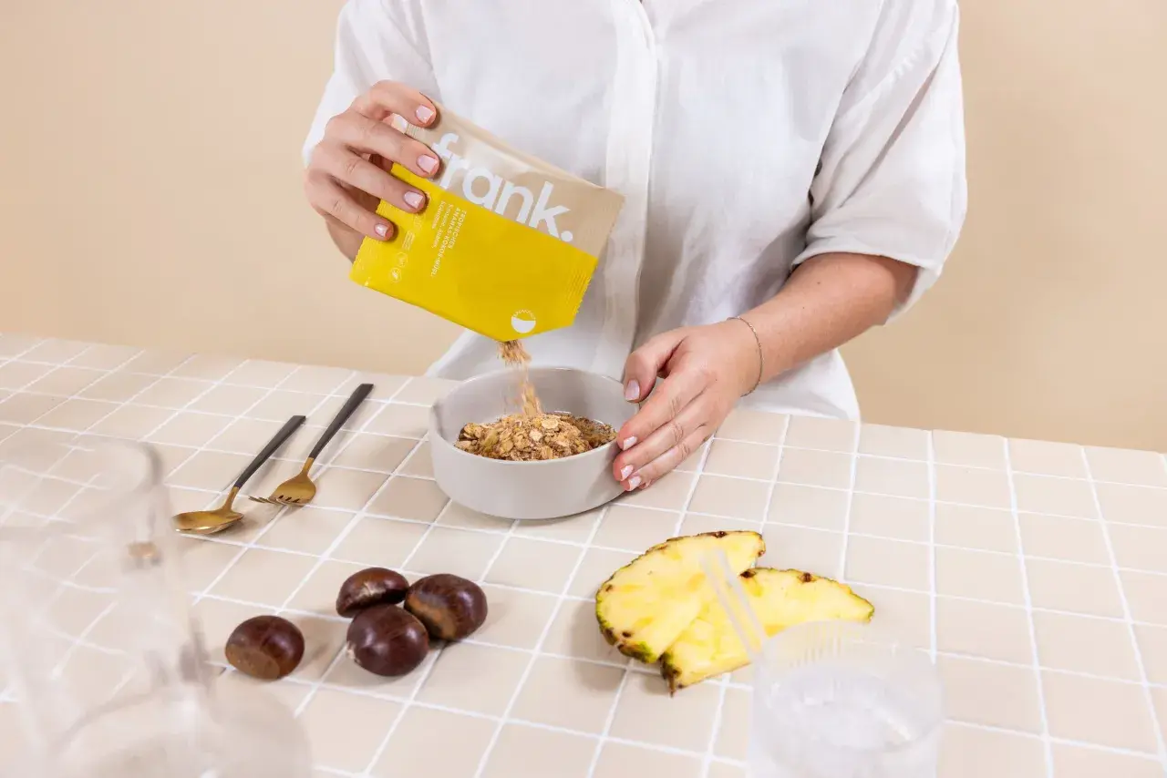 Frau gibt Müsli in eine Schüssel. Das ist Teil der Intervallfasten Regeln für ein gesundes Frühstück.