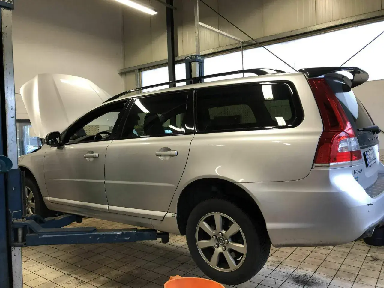 Silberner Volvo Kombi auf Hebebühne, Motorhaube offen. Gute Volvo Geartronic Erfahrungen sind wichtig für die Wartung.