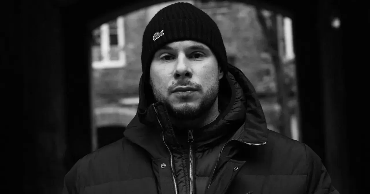 Portret młodego mężczyzny w czapce z logo Lacoste, jednego z wielu polskich raperów, który tworzy muzykę uliczną.