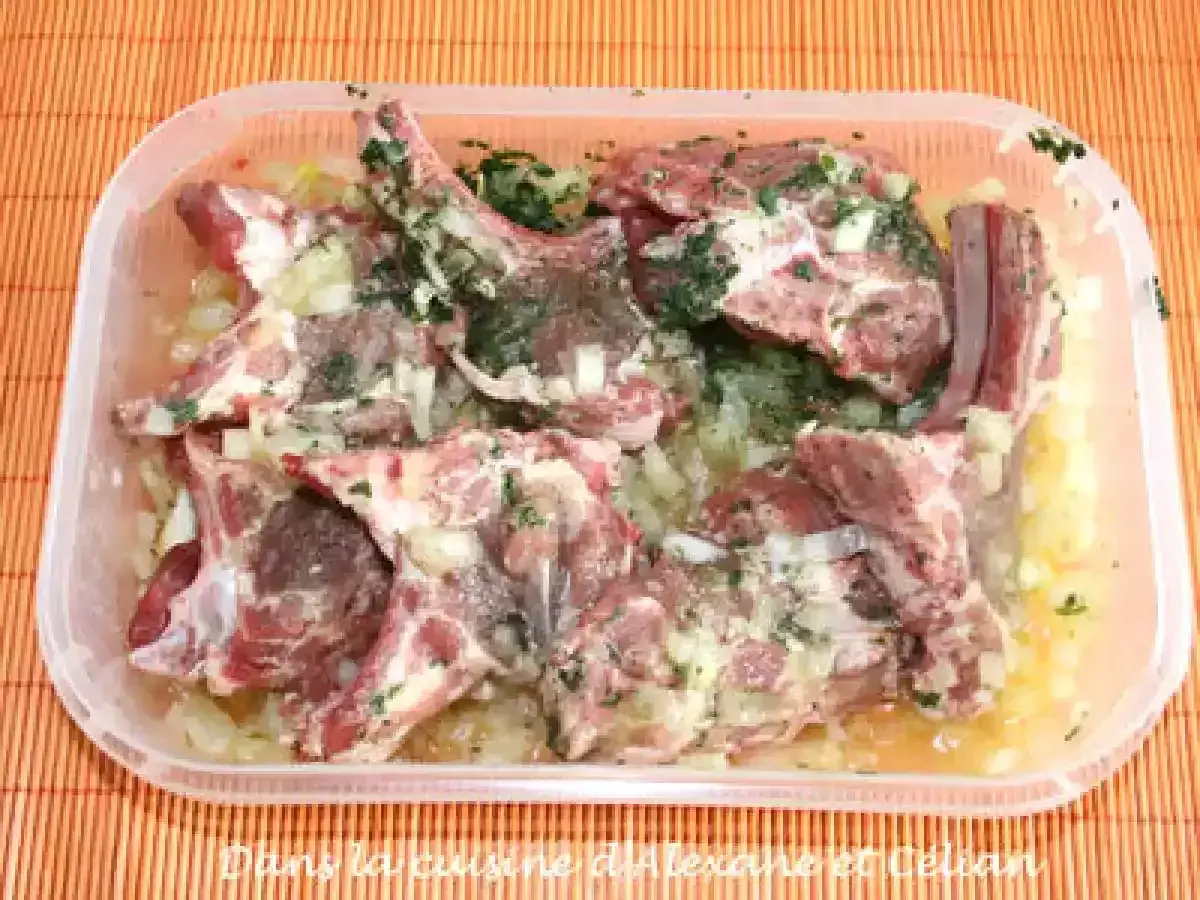 Côtelettes d'agneau crues dans une marinade à l'oignon et aux herbes, prêtes pour une recette de marinade agneau barbecue.