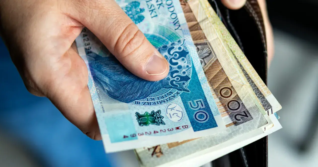 Dłoń trzyma polskie banknoty: 50 zł i 200 zł. Wkrótce trzeba będzie zapłacić czynsz.
