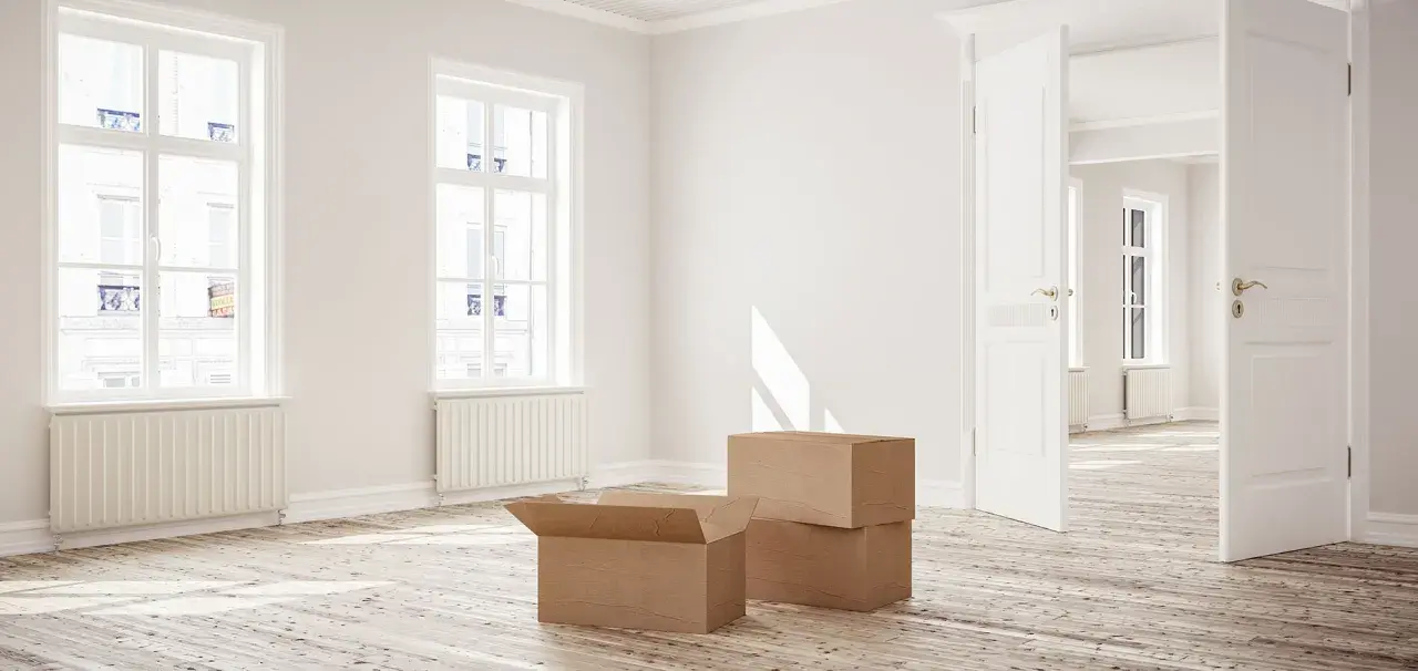 Appartement vide avec cartons, prêt à emménager. La lumière du soleil traverse les fenêtres, évoquant un nouveau départ, peut-être grâce à la loi Borloo.