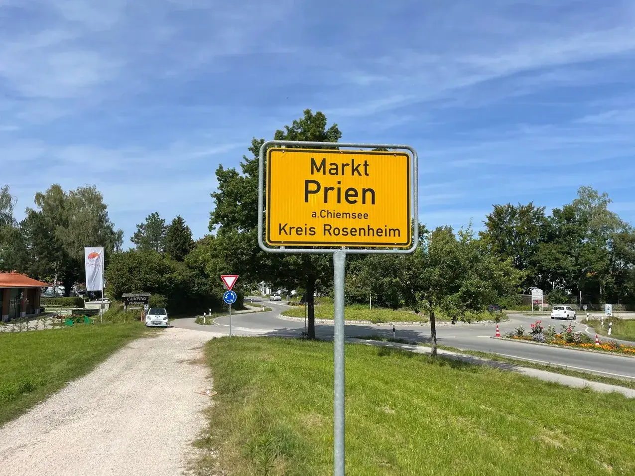 Schild "Markt Prien a.Chiemsee, Kreis Rosenheim" am Ortseingang. Heute ist ein sonniger Tag für den Markt.