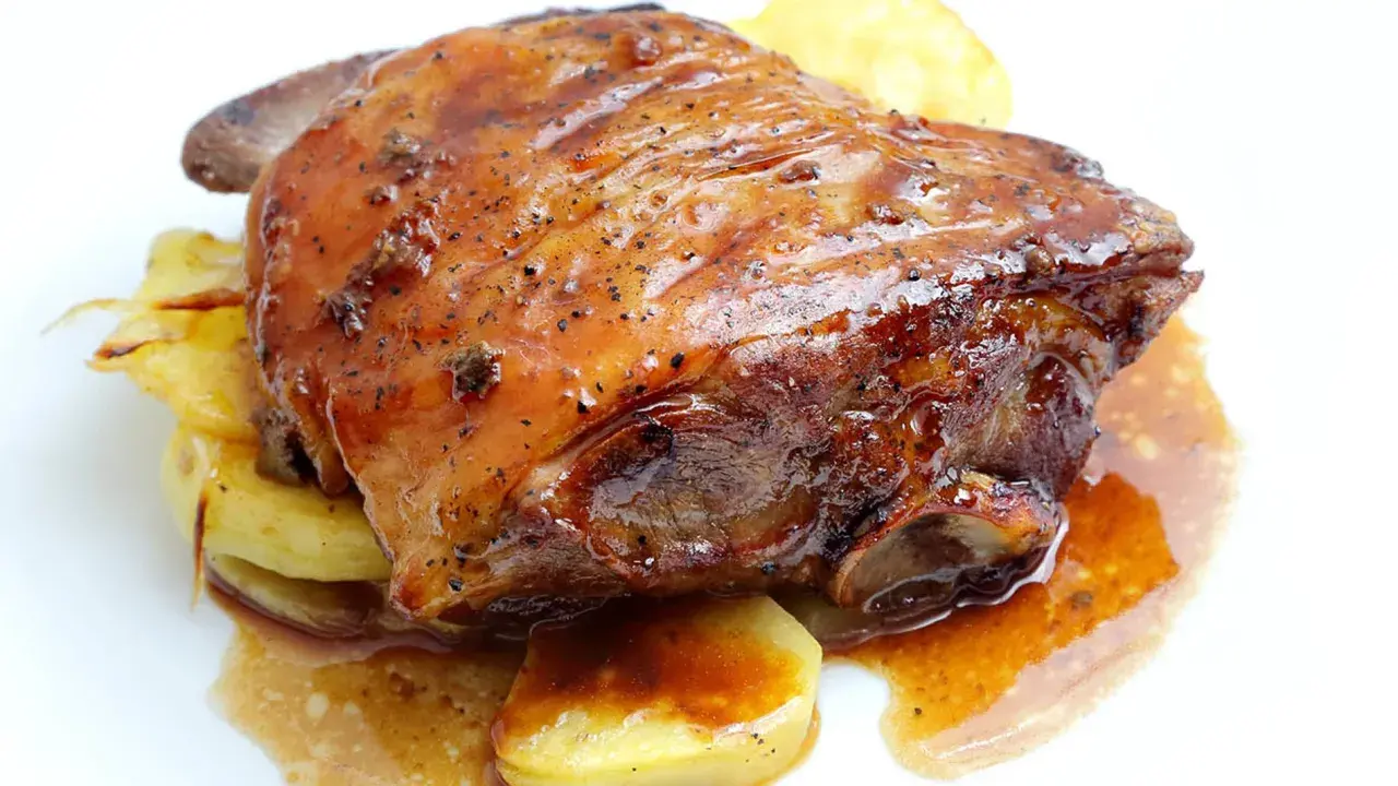 Ternasco asado jugoso y dorado, servido sobre patatas. ¡La mejor opción donde comer ternasco en Zaragoza!