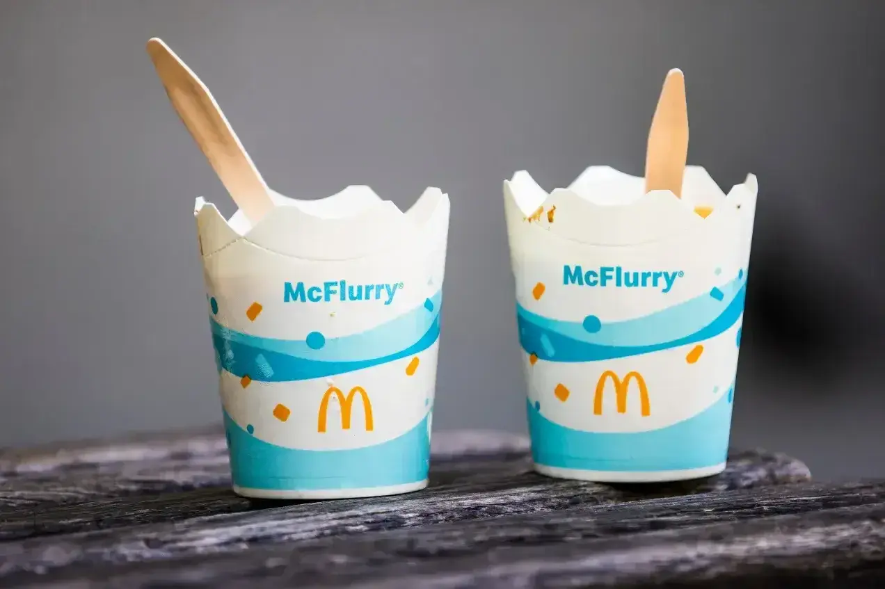 Dwa kubeczki McFlurry z drewnianymi łyżeczkami. Idealne na deser, ale warto sprawdzić mcflurry kcal przed spożyciem.