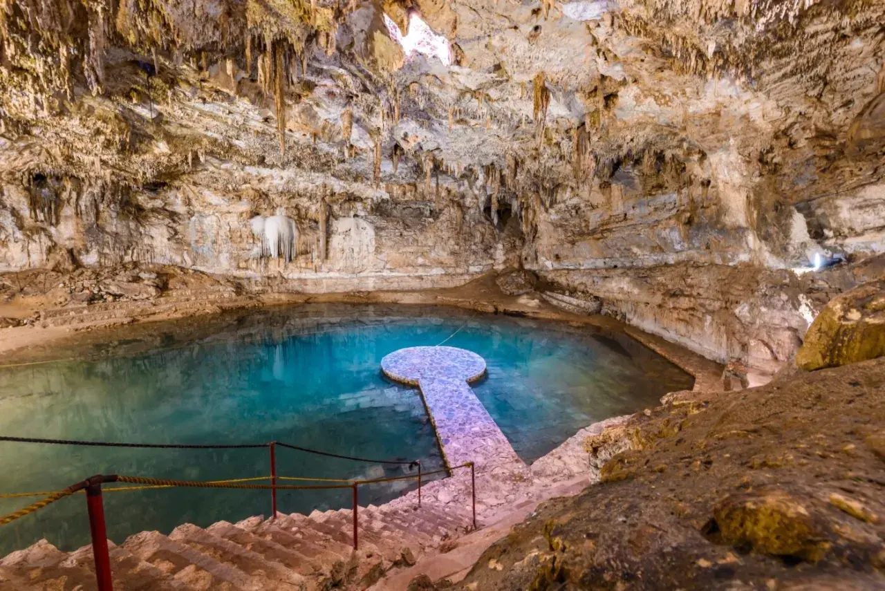 Ein atemberaubender Cenote in Mexiko mit kristallklarem, türkisfarbenem Wasser, Stalaktiten und einer steinernen Plattform.