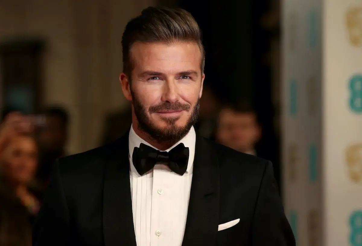 Uomo con impeccabili capelli all'indietro, barba curata e smoking nero con papillon.