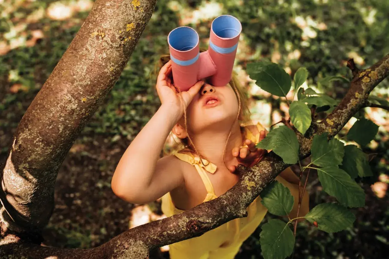 Ein junger Mann mit selbstgebasteltem Fernglas erkundet den Wald.