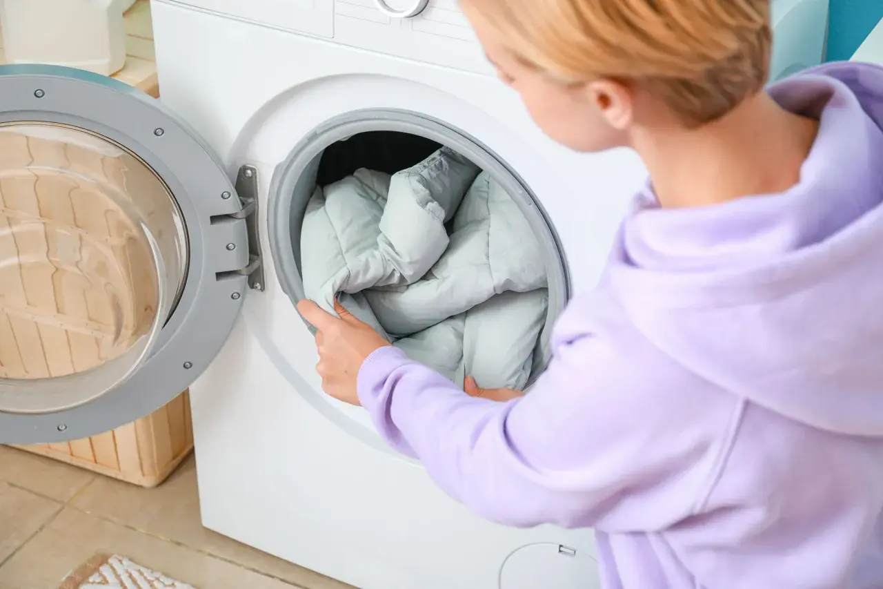 Frau legt eine Daunenjacke in die Waschmaschine. So wird die Daunenjacke gewaschen.
