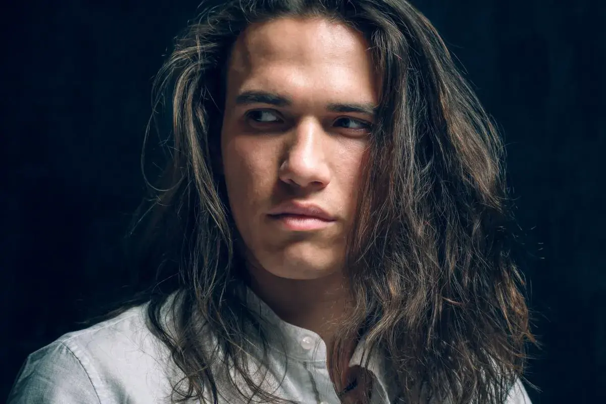 Joven con cabello largo y castaño, con un estilo que resalta el cuidado del cabello hombre.