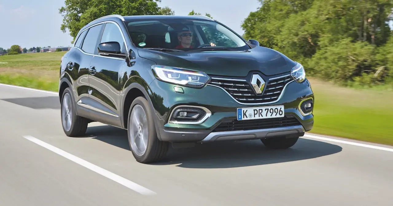 Zielony Renault Kadjar jedzie po drodze, za kierownicą mężczyzna w okularach.