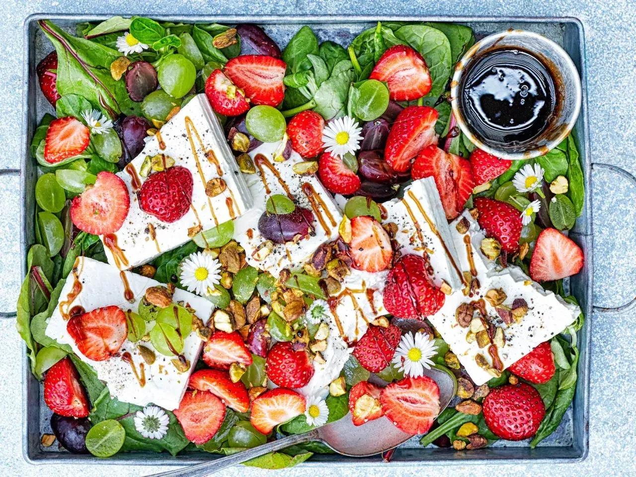 Sommarfräsch sallad med jordgubbar och fetaost, gröna druvor, nötter och en balsamico-dressing.
