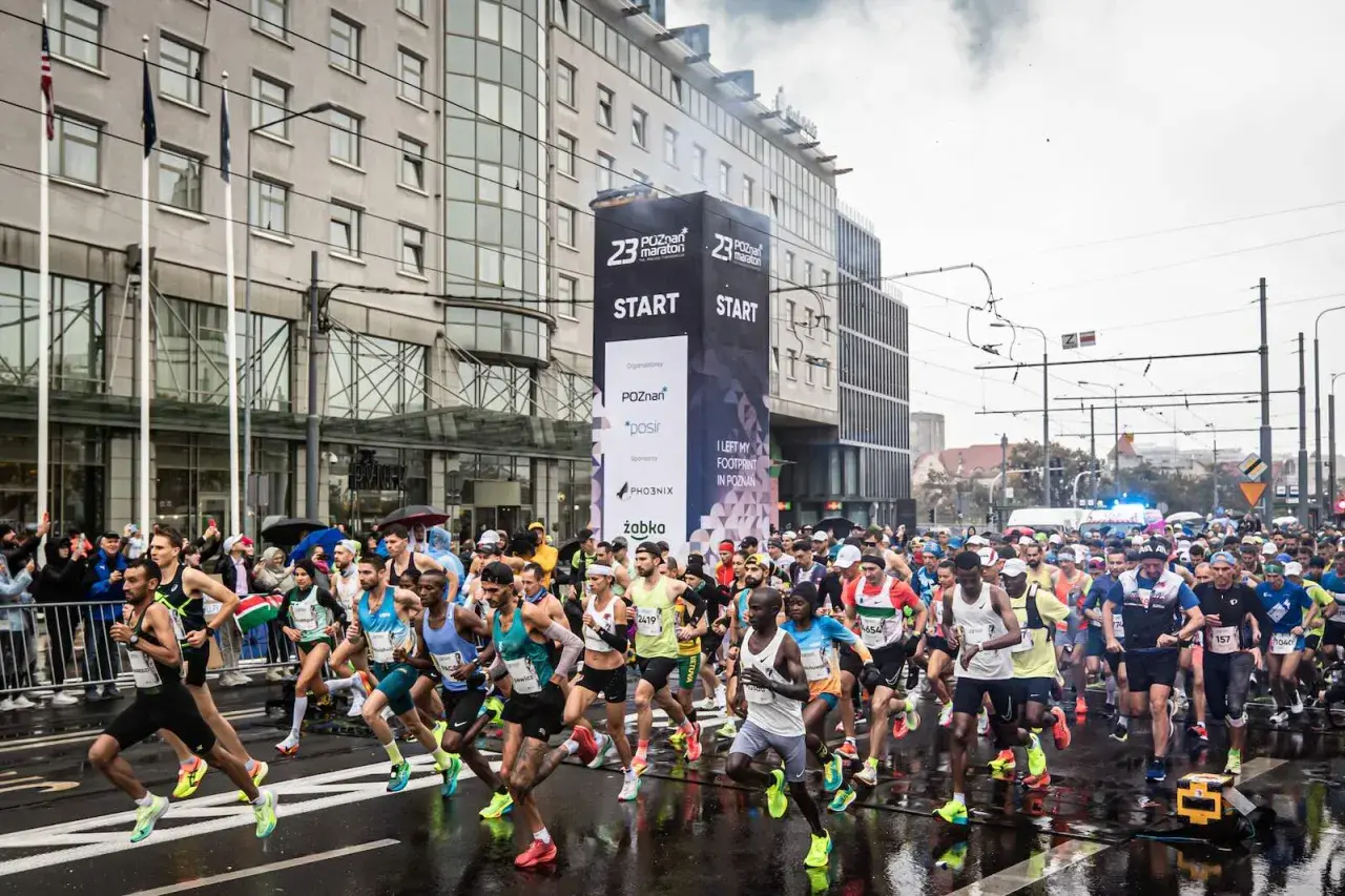 Uczestnicy biegu na 100 km startują w Poznaniu. Tłum biegaczy rusza spod wielkiego banera z napisem "START".