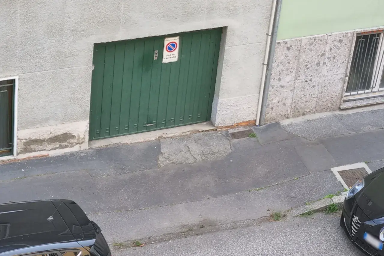 Porta garage verde con cartello "passo carrabile". Spazio di manovra libero.