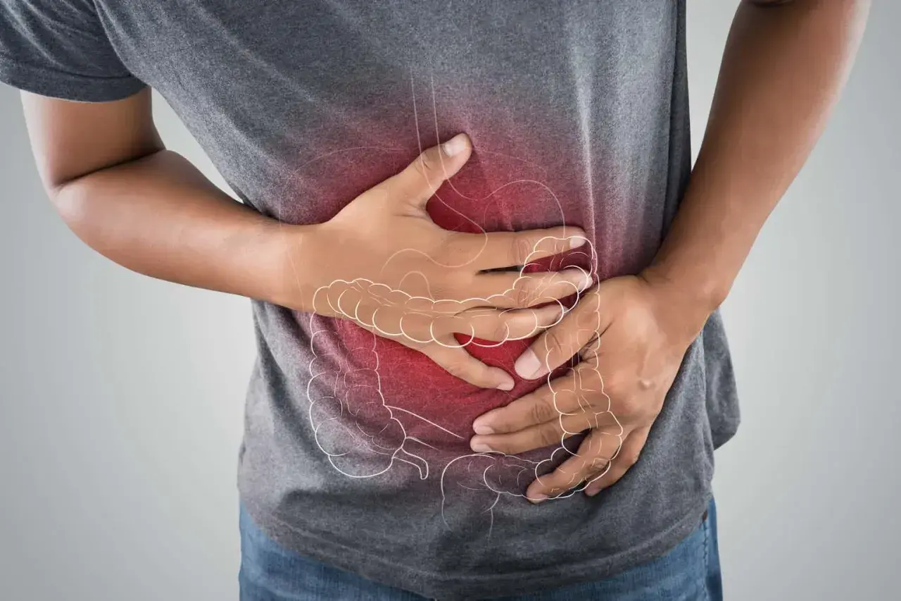 Uomo con mani sull'addome, evidenziato da un'area rossa e un contorno stilizzato dell'intestino. Potrebbe cercare rimedi per la cattiva digestione.