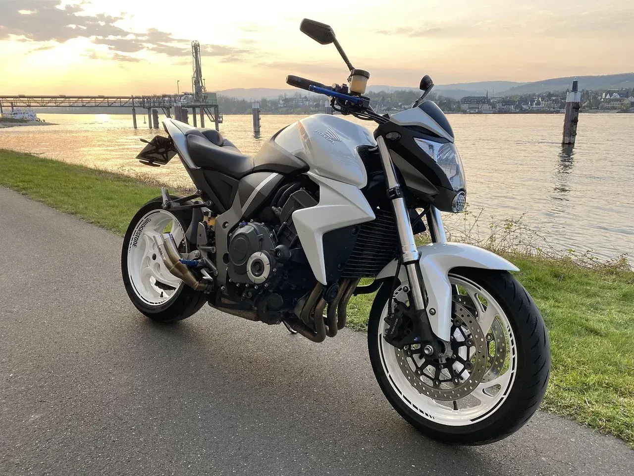 Biały motocykl turystyczny Honda zaparkowany nad rzeką o zachodzie słońca.