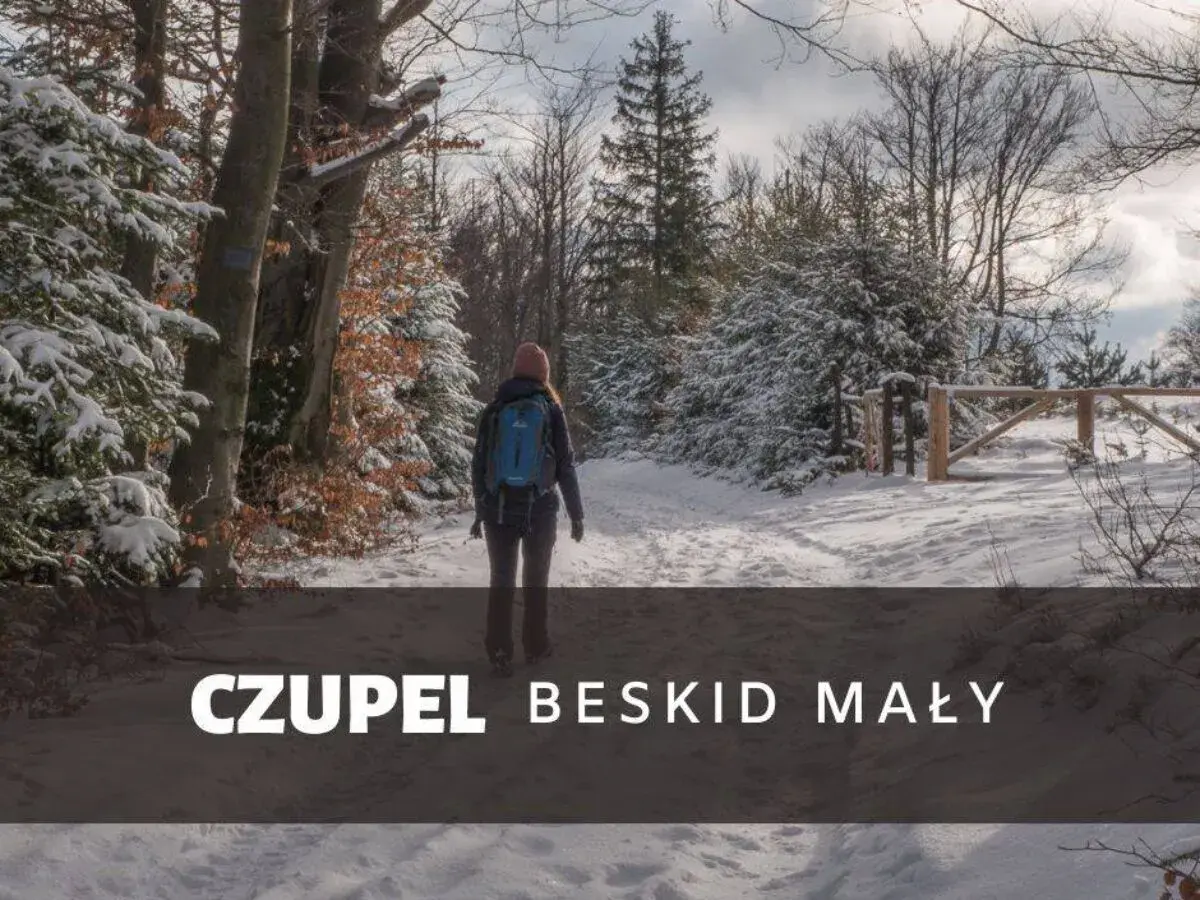 Kobieta z plecakiem idzie zimowym szlakiem w Beskidzie Małym. To czupel najładniejszy szlak, pokryty śniegiem.