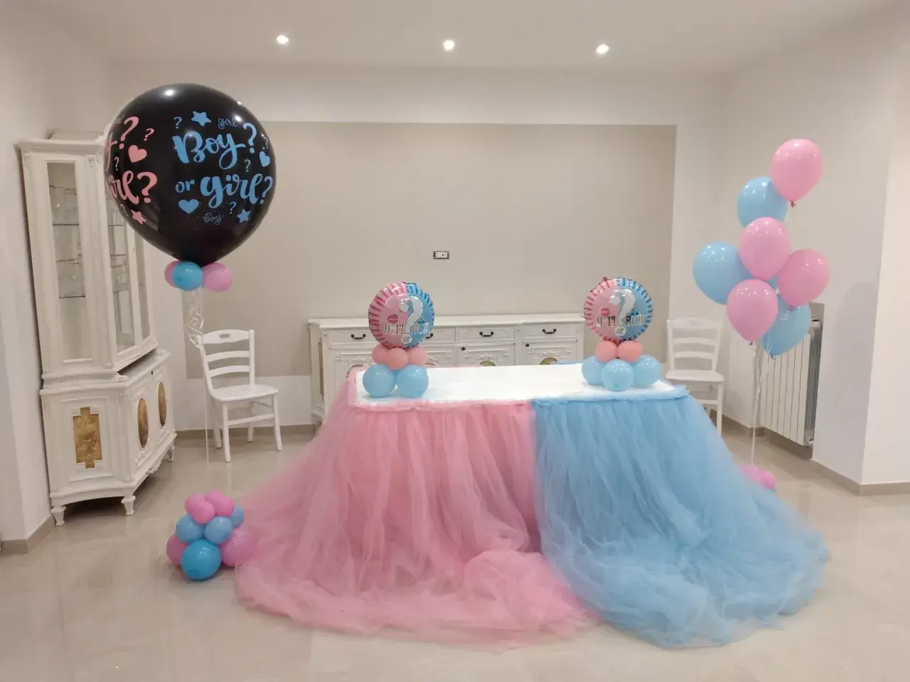 Un allestimento per un baby shower con palloncini rosa e azzurri, che simboleggiano il significato di "boy or girl?".